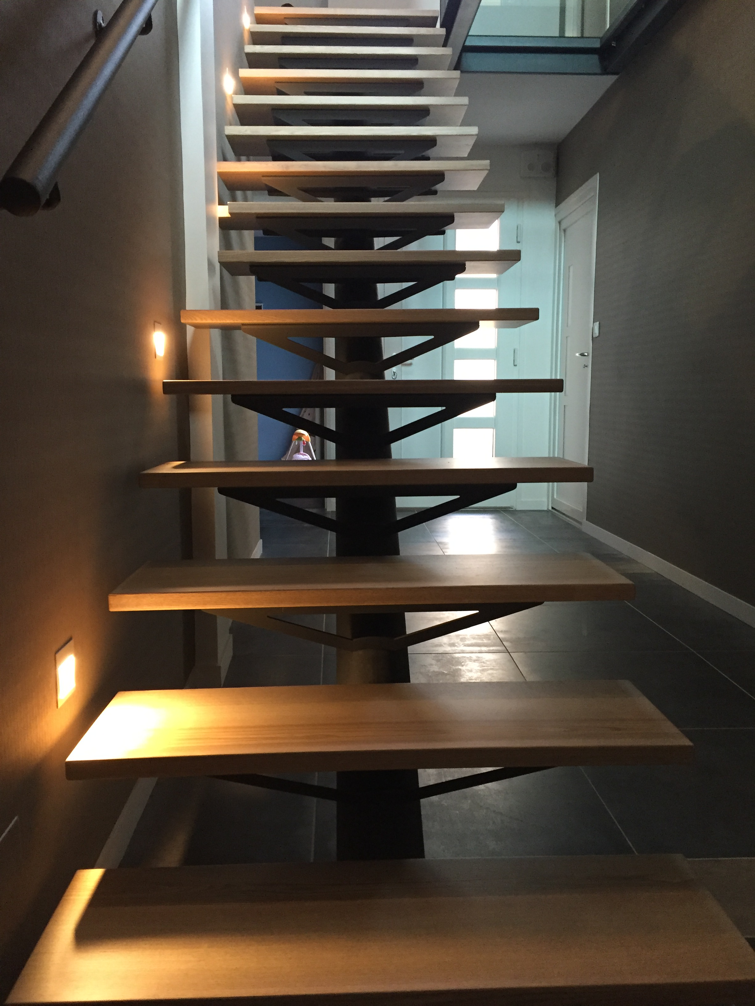 Vue depuis le bas d’un escalier suspendu en métal noir et marches en bois