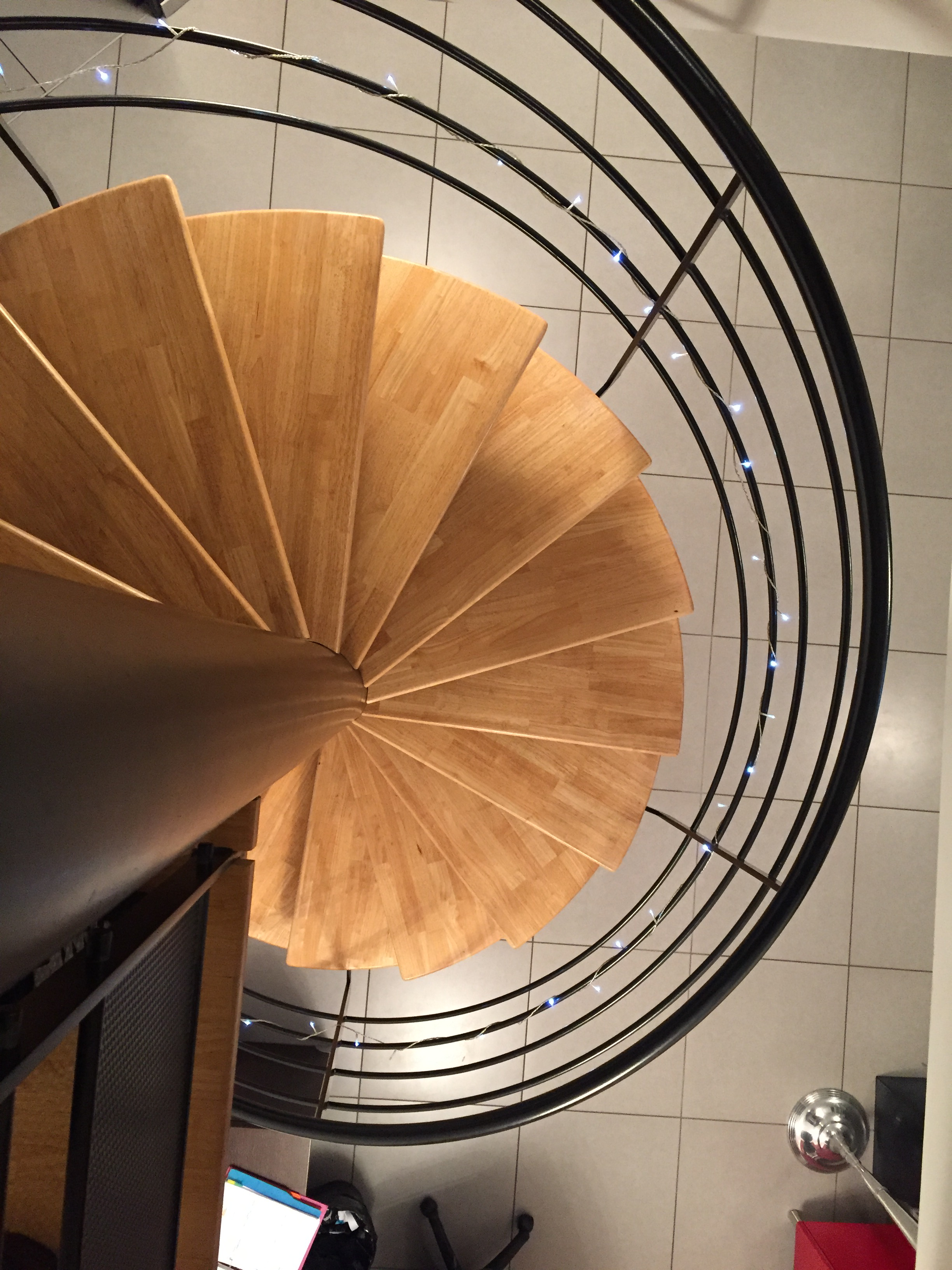 Escalier colimaçon sur mesure avec marches en bois et garde-corps métallique noir