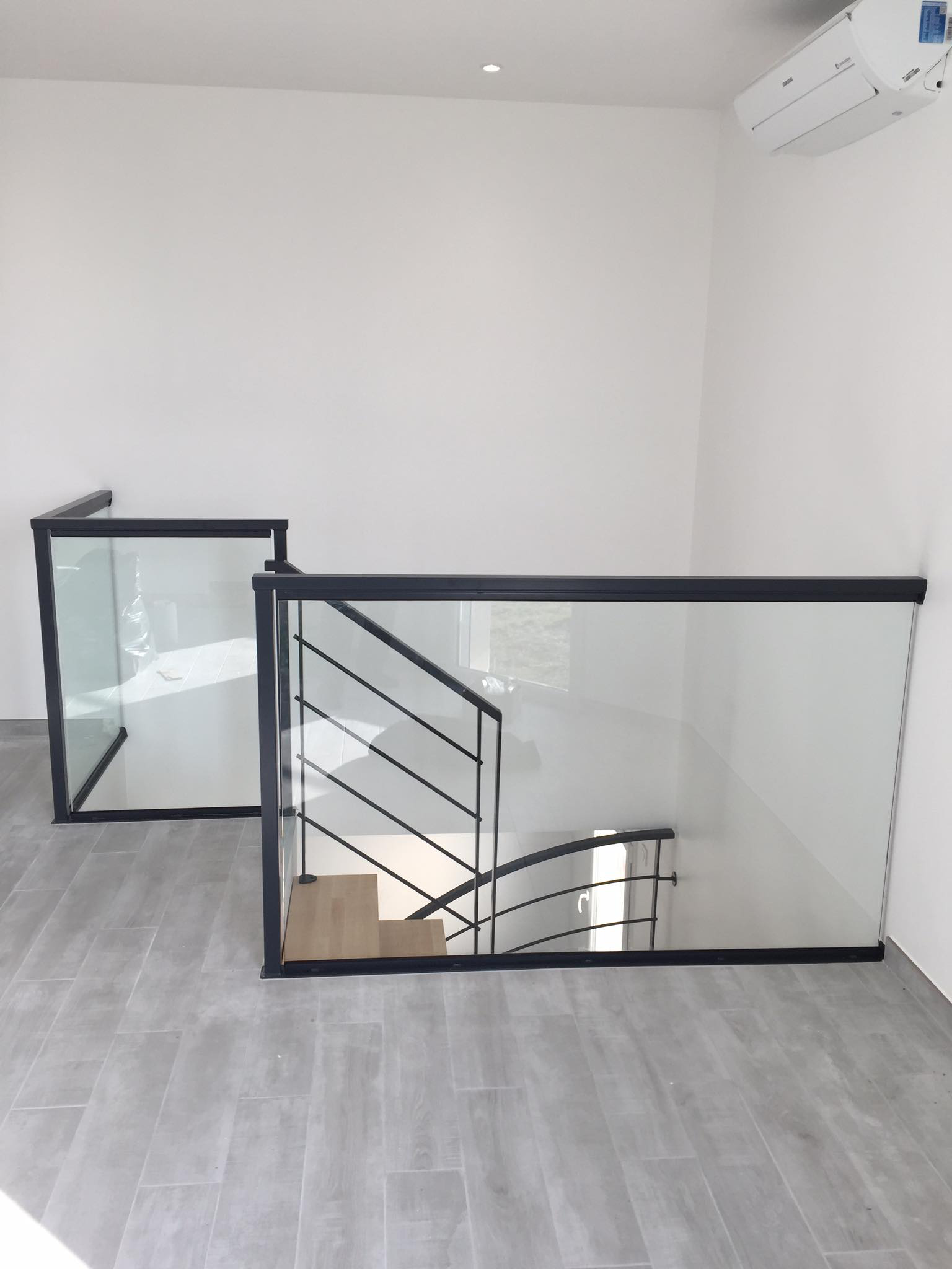 Garde-corps intérieur en métal noir autour d’un escalier avec cloison vitrée