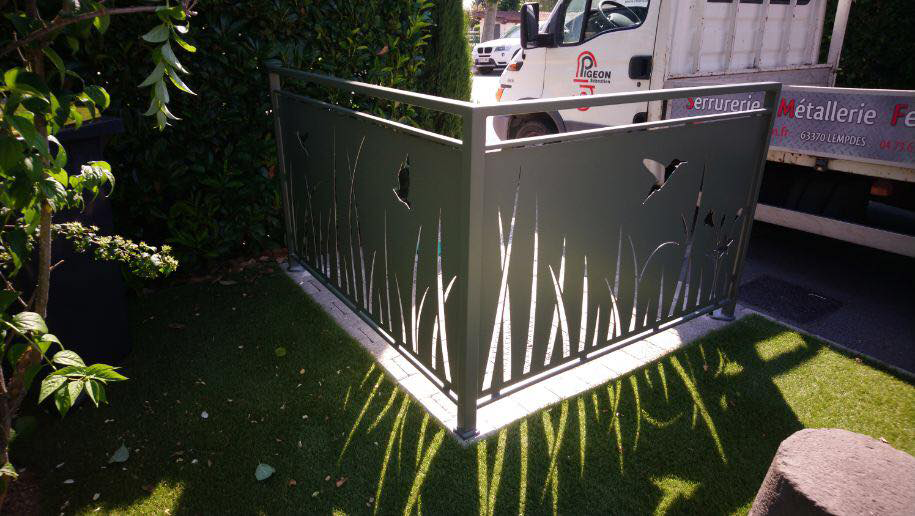 Garde-Corps verts avec découpe plasma en forme d'herbe et papillons, avec l'orientation du soleil, les dessins de la découpe plasma sont refletés en ombre sur l'herbe