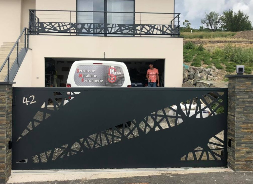 Portail coulissant en métal noir avec motifs géométriques découpés en rappel au garde-crops du balcon