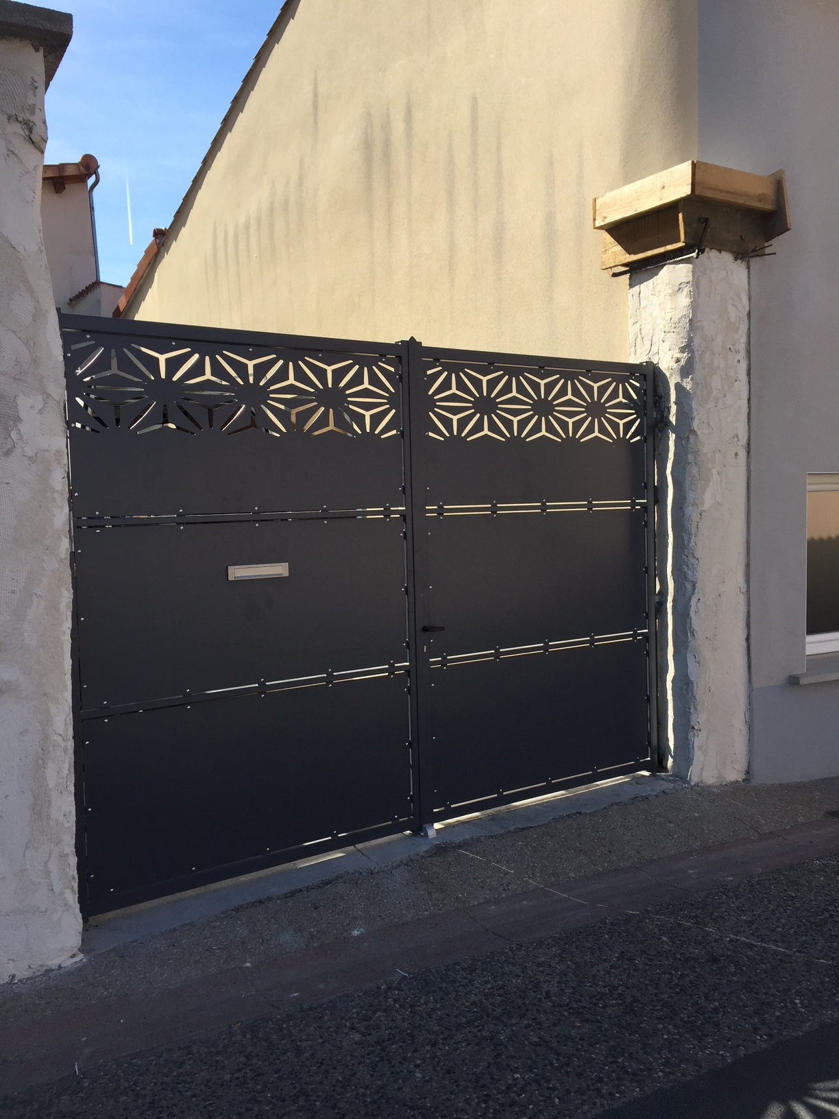 Portail extérieur noir en métal avec motif décoratif découpé